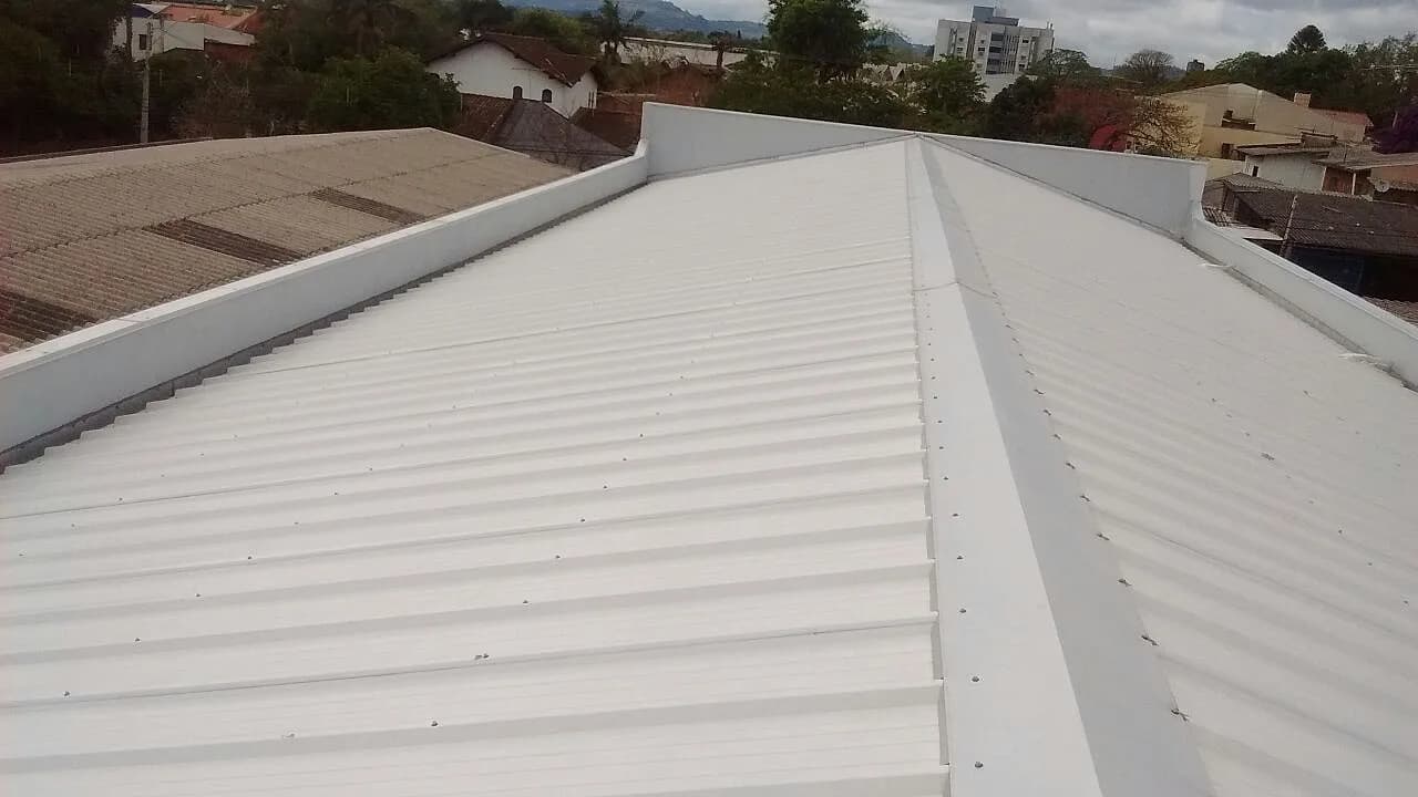 Telhado metálico instalado em residência, bairro ao fundo · Telhas Ivoti